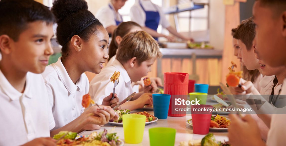 Primary school kids eat lunch in school cafeteria, close up
